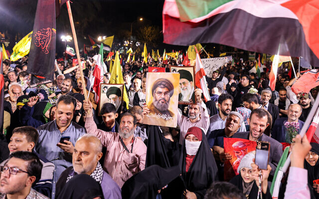 Une femme tenant une pancarte montrant le visage du leader assassiné du Hezbollah, Hassan Nasrallah, avec le slogan en farsi « Le Hezbollah est vivant », lors d'un rassemblement célébrant le lancement par l'Iran d'un barrage de missiles sur Israël, sur la Place de Palestine à Téhéran, le 1er octobre 2024. (Crédit : Atta Kenare/AFP) Une femme tenant une pancarte montrant le visage du leader assassiné du Hezbollah, Hassan Nasrallah, avec le slogan en farsi « Le Hezbollah est vivant », lors d'un rassemblement célébrant le lancement par l'Iran d'un barrage de missiles sur Israël, sur la Place de Palestine à Téhéran, le 1er octobre 2024. (Crédit : Atta Kenare/AFP)