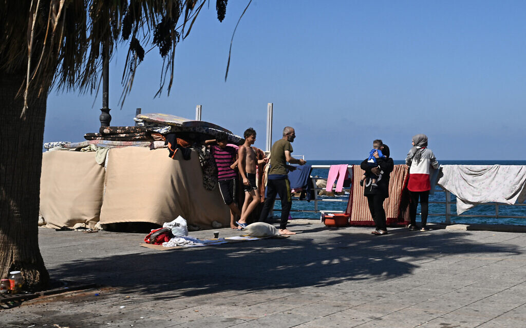 Des personnes déplacées rassemblés près d'une tente le long de la promenade de la corniche de Beyrouth, le 5 octobre 2024. (Crédit : Joseph Eid/AFP)