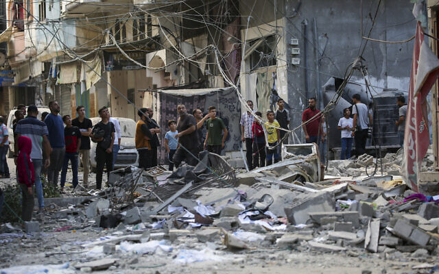 Des personnes inspectant les dégâts causés par une frappe aérienne israélienne sur le camp de réfugiés de Bureij, dans le centre de la bande de Gaza, le 8 octobre 2024 (Crédit : Eyad Baba/AFP)