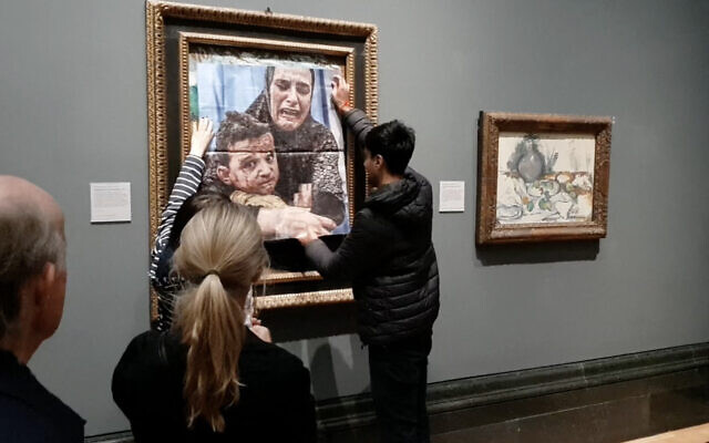 Une photo du groupe de campagne Youth Demand montrant un activiste collant une photo d'une mère et d'un enfant de Gaza sur une œuvre de Picasso intitulée « La Maternité », à la National Gallery, dans le centre de Londres, le 9 octobre 2024. (Crédit : Youth Demand/AFP) Une photo du groupe de campagne Youth Demand montrant un activiste collant une photo d'une mère et d'un enfant de Gaza sur une œuvre de Picasso intitulée « La Maternité », à la National Gallery, dans le centre de Londres, le 9 octobre 2024. (Crédit : Youth Demand/AFP)