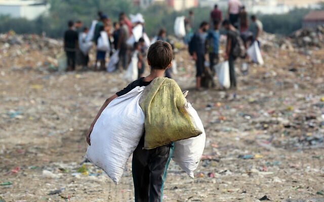 Des enfants examinant des déchets dans une décharge à Khan Younès, dans le sud de la bande de Gaza, le 15 octobre 2024. (Crédit : Bashar Taleb/AFP)