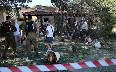 Des forces de sécurité parlant à des résidents à l'intérieur d'une zone bouclée près d'une maison touchée par une roquette tirée depuis le Liban, à Ein Hamifratz près d'Acre dans le nord d'Israël, le 19 octobre 2024. (Crédit : Jack Guez/AFP)