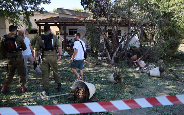 Des forces de sécurité parlant à des résidents à l'intérieur d'une zone bouclée près d'une maison touchée par une roquette tirée depuis le Liban, à Ein Hamifratz près d'Acre dans le nord d'Israël, le 19 octobre 2024. (Crédit : Jack Guez/AFP)