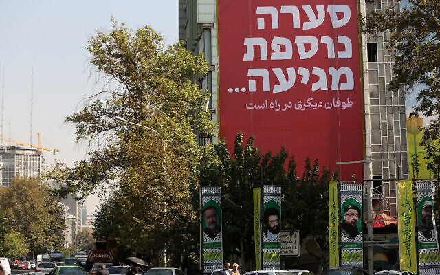 Des passants marchent devant un panneau d'affichage portant un message en farsi et en hébreu qui dit « une autre tempête arrive », à Téhéran, le 27 octobre 2024. (Atta Kenare/AFP)