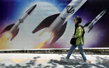Une femme passe devant une bannière montrant des missiles en cours de lancement, dans le nord de Téhéran, en Iran, le 19 avril 2024. (Crédit : AP Photo/Vahid Salemi)