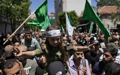 Illustration : Un Palestinien portant une fillette avec un bandeau du groupe terroriste palestinien du Hamas sur lequel on peut lire " les Brigades Ezzedine al-Qassam ", tandis que d'autres arborent des drapeaux du Hamas, alors qu'ils protestent contre l’élimination du chef du Hamas Ismaïl Haniyeh, à Ramallah, en Cisjordanie, le 31 juillet 2024. (Crédit : Nasser Nasser/AP)