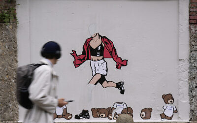 Un homme passe devant la peinture murale vandalisée "7 octobre, fuite" de l'artiste italien AleXsandro Palombo, dans le centre de Milan, en Italie, le 7 octobre 2024. (Crédit : AP Photo/ Antonio Calanni)