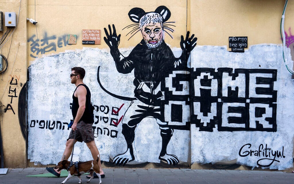 Des gens passant devant un graffiti récemment peint représentant le chef du Hamas Yahya Sinwar, quelques jours après qu'il a été tué par les troupes israéliennes à Gaza, à Tel Aviv, le 20 octobre 2024. (Crédit : Oded Balilty/AP)