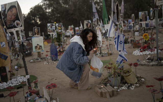Une femme allumant des bougies sur le site du festival de musique Nova, où des centaines de festivaliers ont été tués ou enlevés par le Hamas, lors de la fête juive de Simhat Torah, marquant un an dans le calendrier hébraïque depuis le pogrom, près du kibboutz Reïm, dans le sud d'Israël, le 24 octobre 2024. (Crédit : Maya Alleruzzo/AP)