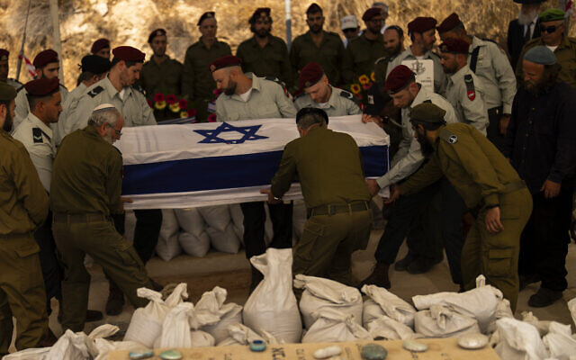 Des soldats israéliens descendent dans la tombe le cercueil recouvert d'un drapeaux du réserviste Yedidia Bloch, 31 ans, lors de ses funérailles dans la colonie de Mevo Horon, en Cisjordanie, le 30 octobre 2024 (AP Photo/Francisco Seco).