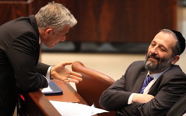Le ministre des Finances de l'époque, Yair Lapid, s'entretient avec le président du Shas, Aryeh Deri, à la Knesset en mars 2013. (Crédit : Isaac Harari/Flash90) Le ministre des Finances de l'époque, Yair Lapid, s'entretient avec le président du Shas, Aryeh Deri, à la Knesset en mars 2013. (Crédit : Isaac Harari/Flash90)