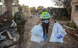 Des volontaires de ZAKA marchant à travers les destructions causées par les terroristes du Hamas ramassant les cadavres, dans le kibboutz Kfar Aza, le 15 octobre 2023. (Crédit : Edi Israel/Flash90)