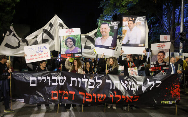 Des manifestants rassemblés à la fin de Simhat Torah pour exiger un accord sur la libération des otages détenus par le Hamas à Gaza, près du domicile du Premier ministre Benjamin Netanyahu, à Jérusalem, le 24 octobre 2024. La banderole se lit comme suit : "Retarder la libération des captifs revient à verser du sang". (Crédit : Forum des familles des otages et disparus)