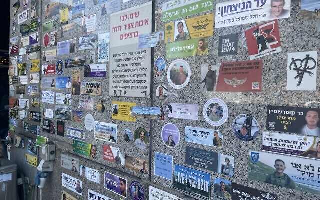 Un mur de la gare de Hashalom remplis de  tous les autocollants commémorant les victimes tuées le 7 octobre et dans la guerre en cours. (Crédit : Jessica Steinberg/Times of Israel).
