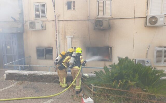 Des pompiers s'efforçant d'éteindre un incendie dans une maison suite à l'impact d'une roquette à Kiryat Shmona, le 9 octobre 2024. (Crédit : Services d'incendie et de secours)