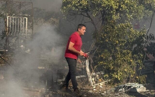 Des voisins tentent d'éteindre des incendies après un tir de roquette sur une maison à Netiv Hashayara, le 24 octobre 2024. (Crédit : Margalit Boyarsky)