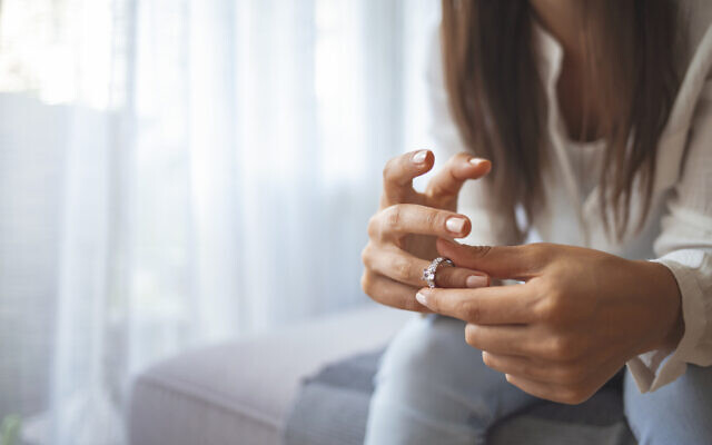 Illustration : Une femme retirant son alliance. (Crédit : Dragana991/iStock)