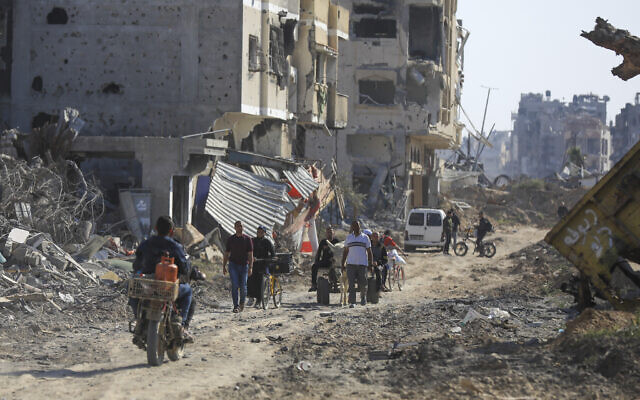 Des Palestiniens marchent dans des rues détruites dans le cadre de l'offensive aérienne et terrestre israélienne alors que l'armée vient de se retirer de Khan Younès,  dans le sud de la bande de Gaza, le 7 avril 2024. (Crédit : AP Photo/ Ismael Abu Dayyah)