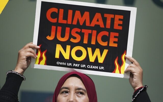 Une manifestante tient une pancarte sur laquelle est écrit « Justice climatique maintenant » lors de la conférence des Nations unies sur le climat COP29, le 18 novembre 2024, à Bakou, en Azerbaïdjan. (Crédit : Sergei Grits/AP)