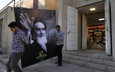 Deux hommes portent une bannière de l'Ayatollah Khomeini, fondateur de la révolution iranienne, à l'entrée de l'ancienne ambassade américaine, qui a été transformée en musée anti-américain, à Téhéran, en Iran, le mardi 22 octobre 2024. (AP Photo/Vahid Salemi) Deux hommes portent une bannière de l'Ayatollah Khomeini, fondateur de la révolution iranienne, à l'entrée de l'ancienne ambassade américaine, qui a été transformée en musée anti-américain, à Téhéran, en Iran, le mardi 22 octobre 2024. (AP Photo/Vahid Salemi)