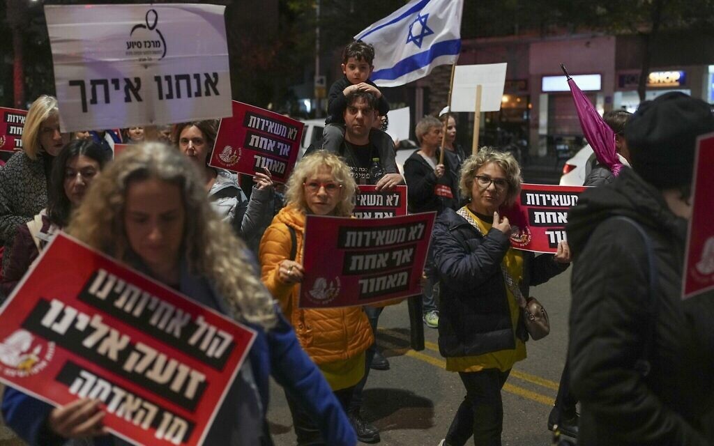 Des manifestants rappellent le sort des femmes otages détenues à Gaza lors d'une marche organisée à l'occasion de la Journée internationale pour l'élimination de la violence à l'égard des femmes, à Tel-Aviv, le 25 novembre 2024. Des pancartes en hébreu indiquent "Les voix de nos sœurs nous crient depuis la terre" et "Nous ne laissons personne derrière nous". (Crédit : AP Photo/Ohad Zwigenberg).