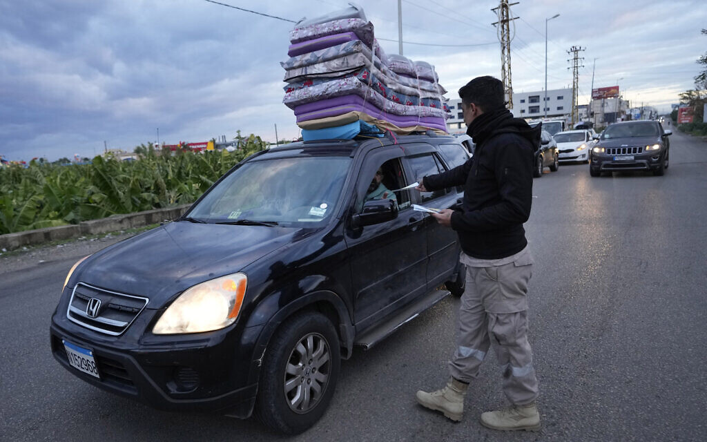 Un membre de la défense civile distribue des dépliants sécuritaires aux personnes retournant dans leurs villages après le cessez-le-feu entre le Hezbollah et Israël, à Tyr, au sud du Liban, le mercredi 27 novembre 2024. (Crédit : AP/Hussein Malla)