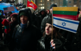Une manifestante brandit un drapeau de la Lituanie et d'Israël lors d'une manifestation silencieuse sur la place de l'Indépendance devant le Parlement à Vilnius, en Lituanie, le 14 novembre 2024, contre l'inclusion d'un parti dont le chef est jugé pour des propos antisémites présumés dans la coalition au pouvoir. (Crédit : Petras Malukas / AFP)