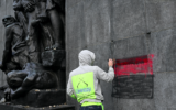 Un ouvrier nettoie la tache de peinture rouge et noire sur un monument commémorant le soulèvement du ghetto de Varsovie, en Pologne, le 15 novembre 2024. (Crédit : Sergei GAPON / AFP)