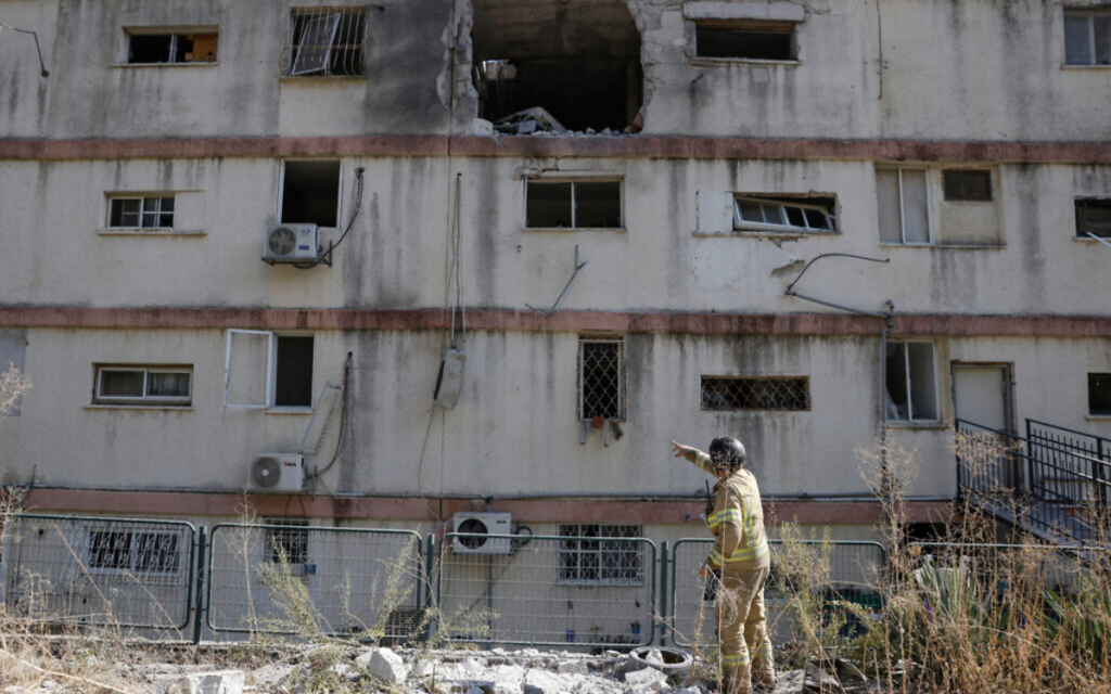 Les forces de sécurité israéliennes et le personnel d'urgence dans un immeuble touché par des roquettes tirées depuis le Liban, dans la ville de Kiryat Shmona, au nord du pays, le 20 novembre 2024. (Crédit : Jalaa Marey/AFP)