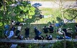 Des personnes se mettent à l'abri alors que les sirènes préviennent de l'arrivée de missiles en provenance du Liban lors des funérailles de Sivan Sade, 18 ans, tué par des éclats de missiles alors qu'il travaillait dans un champ, dans le kibboutz Kfar Masaryk, dans le nord d'Israël, le 8 novembre 2024. (Crédit : Flash90)