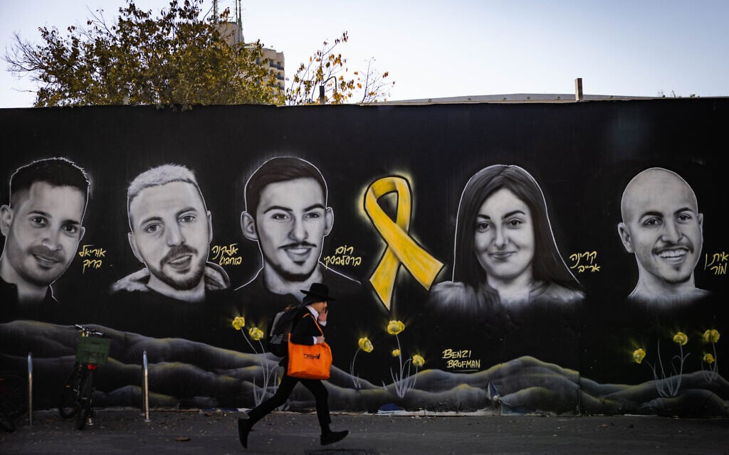 Des personnes marchent à côté d'une peinture murale représentant des Israéliens pris en otage dans la bande de Gaza, à Jérusalem, le 22 novembre 2024. (Yonatan Sindel/Flash90)
