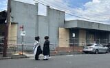 Deux Juifs devant la synagogue Adass Israel à Ripponlea, Melbourne, le lendemain de l'incendie criminel qui l'a ravagée, le 7 décembre 2024. (Crédit : Rachael Ward/AP/Reuters)