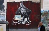 Des hommes passant devant une section de la barrière de sécurité israélienne peinte avec un portrait du terroriste palestinien condamné Marwan Barghouti, détenu dans une prison israélienne, à Bethléem, en Cisjordanie, le 6 novembre 2023. (Crédit : Hazem Bader/AFP)