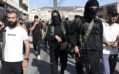 Des individus armés, dont l'un porte un bandeau du Jihad islamique palestinien, participant à une procession funéraire pour des Palestiniens tués par une frappe aérienne israélienne, à Tubas, dans le nord de la Cisjordanie, le 13 septembre 2024. L'armée a déclaré que la frappe visait cinq terroristes. (Crédit : Jaafar Ashtiyeh/AFP)