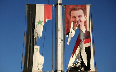 Un panneau d'affichage portant une photo du président syrien Bachar al-Assad et un drapeau national sont déchirés par des combattants anti-gouvernementaux dans la ville d'Alep, au nord du pays, le 30 novembre 2024. (Crédit : Omar Haj Kadour / AFP)