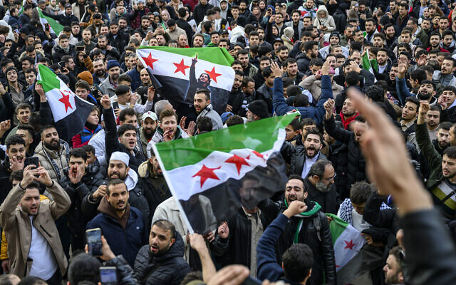 Des membres de la communauté syrienne brandissant des drapeaux syriens et célébrant la fin du régime du dictateur syrien Bashar el-Assad après que les combattants rebelles ont pris le contrôle de la capitale syrienne, Damas, à Berlin, en Allemagne, le 8 décembre 2024. (Crédit : Frank Zeller/AFP)