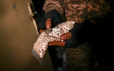 Un combattant rebelle syrien avec un sac contenant des pilules de captagon trouvé à l’aéroport militaire de Mazzeh, à l’ouest de Damas, le 12 décembre 2024. (Aris Messinis/AFP)
