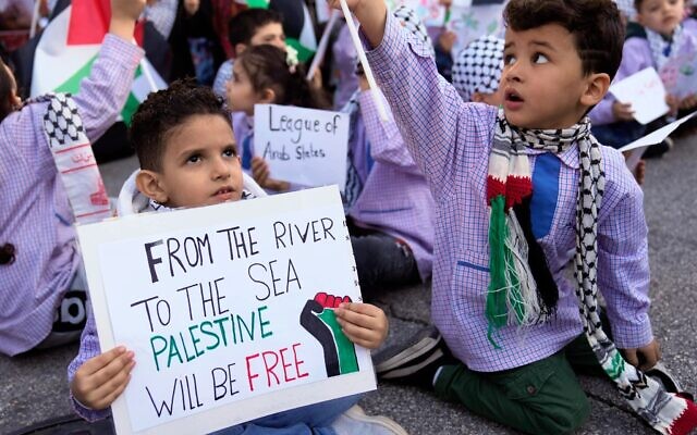 Photo d'illustration : Un petit Palestinien tient une pancarte sur laquelle est écrit "Du fleuve jusqu'à la mer, la Palestine sera libre" à Beyrouth, au Liban, le 14 décembre 2023. (Crédit : AP Photo/Hussein Malla/File)