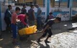 Des Palestiniens recueillent de l'eau potable dans une usine de dessalement qui fonctionne désormais 24 heures sur 24 à Deir al-Balah, dans la bande de Gaza, le 14 novembre 2024. (Crédit : AP/Abdel Kareem Hana)