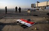 Un drapeau officiel syrien gît au sol non loin d'insurgés islamistes, sur le tarmac de l'aéroport international d'Alep, à Alep, le 2 décembre 2024. (Crédit : AP Photo/Omar Albam)