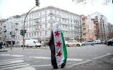 Une jeune fille syrienne portant un drapeau de l'opposition syrienne, dans une rue de Berlin, le 10 décembre 2024. (Crédit : Ebrahim Noroozi/AP)