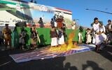 Des partisans houthis brûlent des drapeaux israéliens et américains lors d'un rassemblement anti-israélien à Sanaa, au Yémen, le 27 décembre 2024. (Crédit : AP Photo/Osamah Abdulrahman)