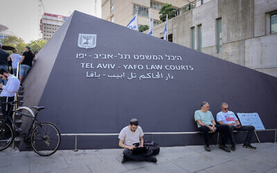 Des personnes assises, devant le tribunal de Tel Aviv, le 21 novembre 2024. (Crédit : Avshalom Sassoni/Flash90)