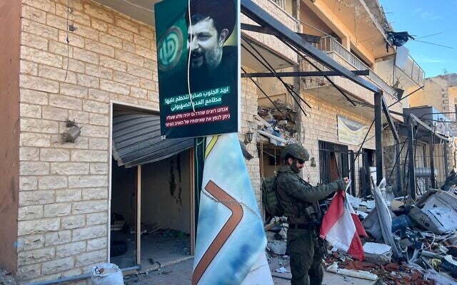 Un soldat de l'armée israélienne de la 91ᵉ division examinant un drapeau libanais, à Meiss El Jabal, au Liban, le 15 décembre 2024. (Crédit : Lazar Berman/Times of Israel)