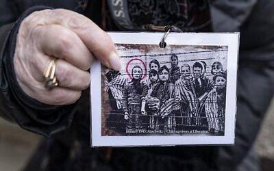 Miriam Ziegler (Friedman), survivante de la Shoah et ancienne prisonnière du camp de la mort nazi d'Auschwitz-Birkenau, montre une photo historique d'elle et d'autres prisonniers à Oswiecim, le 26 janvier 2020, la veille du 75e anniversaire de la libération du camp. (Crédit : Wojtek Radwanski/AFP)
