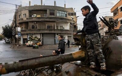 Des enfants syriens jouent sur un char endommagé à Homs, le 20 décembre 2024. (Crédit : Sameer Al-DOUMY / AFP)