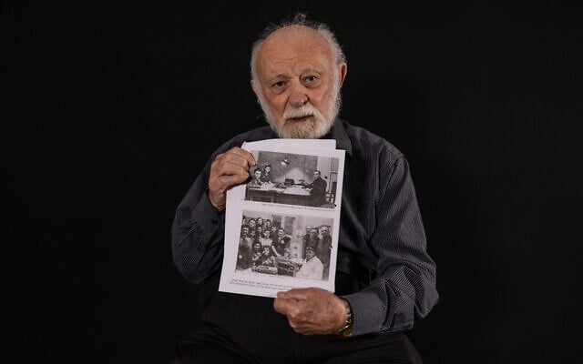 Le photojournaliste et survivant du camp de concentration d'Auschwitz Dan Hadani (né Dunek Zloczewsk) tient une photo de l'usine où il travaillait dans le ghetto de Lodz, chez lui à Givataim, dans le centre d'Israël, le 24 novembre 2024. (Crédit : Menahem Kahana / AFP)