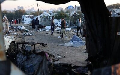 Des Palestiniens marchant au milieu de débris de tentes, après une frappe israélienne sur un camp de déplacés à al-Mawasi, dans le sud de la bande de Gaza, qui aurait fait au moins onze morts, dont le chef de la police du Hamas et son adjoint, le 2 janvier 2025. (Crédit : Bashar Taleb/AFP)