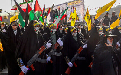 Des membres des forces paramilitaires iraniennes (Bassij) marchent avec des armes lors d'un rassemblement anti-israélien à Téhéran, le 10 janvier 2025. (Crédit : AFP)