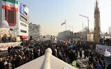 Des membres des forces paramilitaires iraniennes (Basij) marchant à côté d'un missile iranien à longue portée Sejil, lors d'un rassemblement anti-Israël à Téhéran, le 10 janvier 2025. (Crédit : AFP)